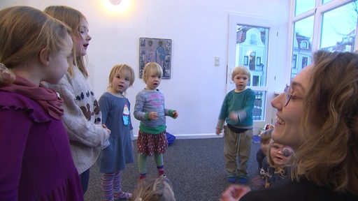 Die Kinder der Dom-Spatzen singen und tanzen mit ihrer Musikpädagogin zusammen.