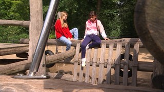 Es sind zwei Kinder zu sehen, welche auf einem Spielplatz spielen.