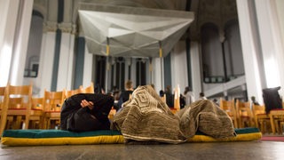 Flüchtlinge liegen auf Matrazen in einer Kirche auf dem Boden (Archivbild)