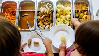Kinder befüllen ihre Teller beim Mittagessen in einer Kita
