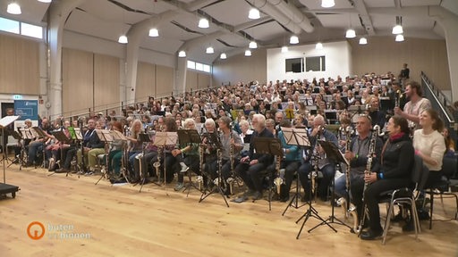 Klarinettenorchester bestehend aus vielen Leuten sitzt in einer großen Halle