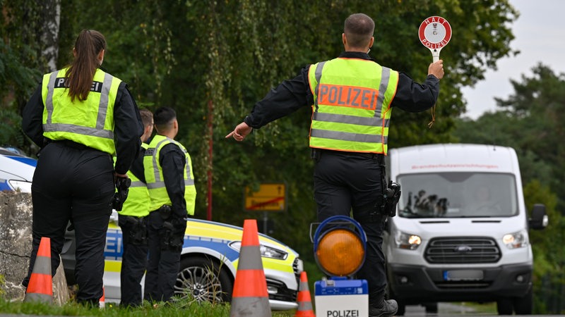 Polizeibeamte stoppen einen Kleintransporter bei einer Kontrolle.