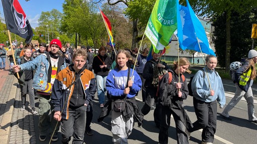 Junge Menschen gehen mit Fahnen und Schildern durch die Bremer Innenstadt.