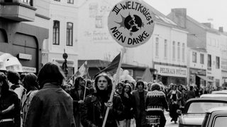 Demonstranten im Steintor-Viertel. Einer trägt ein rundes Schild mit der Aufschrift: "III. Weltkrieg? Nein Danke"