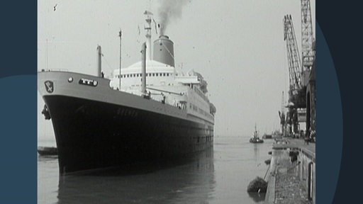 Ein altes Kreuzfahrtschiff fährt in einen Hafen.