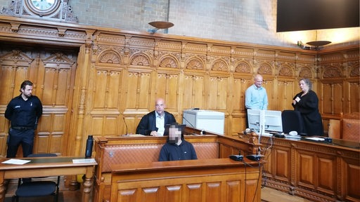 Blick in den Gerichtssaal am Landgericht Bremen: Der Angeklagte (verpixelt) mit Verteidigung und rechts im Bild die Richterin.