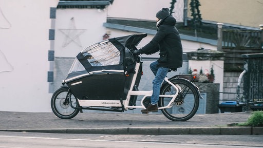 Ein Mann fährt mit einem Lastenrad auf einem Radweg.