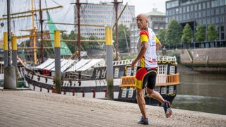 Extremsportler Emin da Silva legt den Bremer Marathon an der Weser rückwärts laufend zurück.