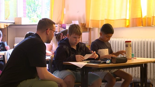 Ein Lehrer spricht mit zwei seiner Schulkindern in der Schule. 