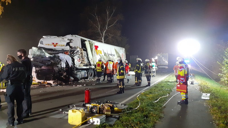 Nach einem Unfall stehe auf der Bundesstraße B6 Polizisten und Feuerwehrleute an einem schwer beschädigten Laster. 