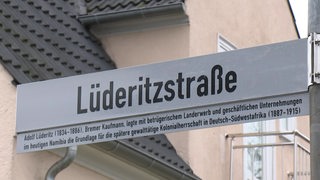 Straßenschild der Lüderitzstraße mit Zusatzschild der geschichtlichen Kontextualisierung