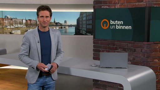 Moderator János Kereszti im Studio von buten un binnen. 