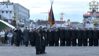 Männer und Frauen in Uniform stehen in Reih und Glied.