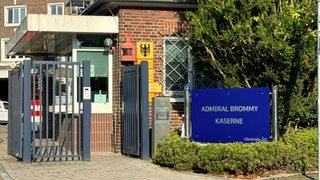 Neben einem Eingangstor steht ein Schild mit der Aufschrift "Admiral Brommy Kaserne".