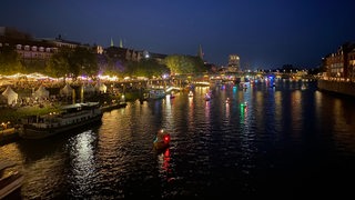 Boote fahren mit bunten Lichtern geschmückt an der Schlachte die Weser entlang.