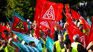 Mit Plakaten und Fahnen stehen die Teilnehmer einer Kundgebung vor der Hauptverwaltung vom Stahlhersteller Arcelormittal.