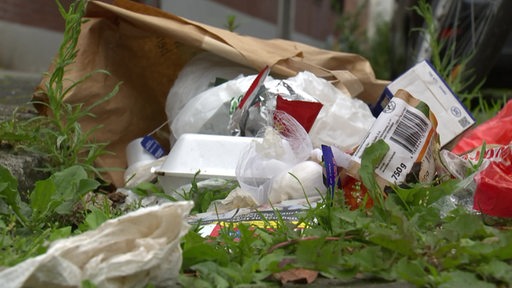 Illegal entsorgter Müll in einem Blumenbeet.