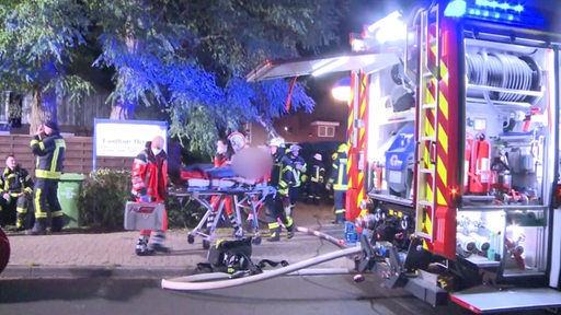 Die Feuerwehr trägt verletzte Senioren aus dem Altersheim nach einem Brand. 