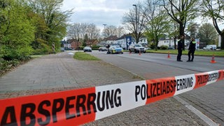 Eine von der Polizei abgesperrte Straßen, zwei Polizisten stehen auf der Straße.