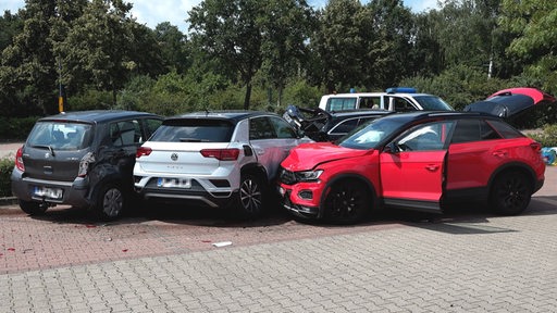 Bild von einem Unfall: Ein roter Wagen ist auf drei andere geparkte Autos aufgefahren 