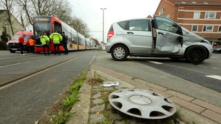 Eine Straßenbahn und ein Auto sind zusammengestoßen. Das Auto ist beschädigt.