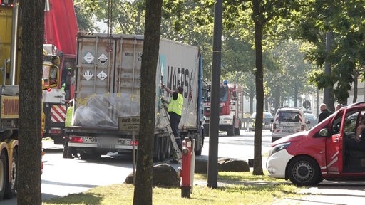 Feuerwehrleute sichern einen Container, der auf einem Lastwagen aufliegt.