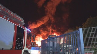 Ein Feuerwehrauto vor dem brennenden Gelände eines Recyclinghofs in Hatten.