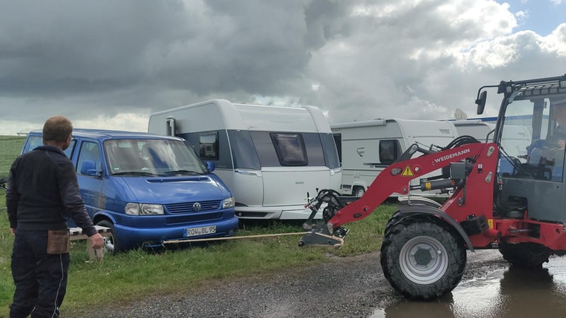 Ein Bagger zieht an einem feststeckenden ein Auto.