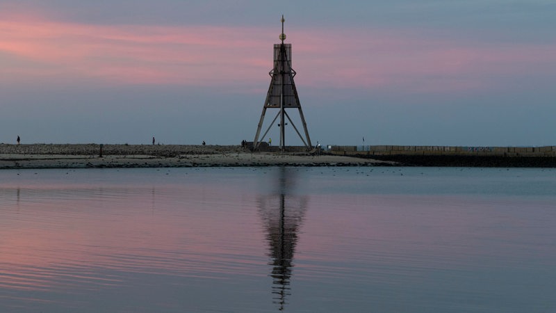 Ein Seezeichen spiegelt sich bei Sonnenuntergang im Wasser.