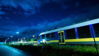 Ein Zug der Nordwestbahn steht im Dunkeln auf einem Gleis.