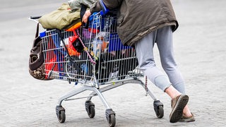 Ein obdachloser Mann läuft mit einem Einkaufwagen über den Platz vor dem Bremer Hauptbahnhof.