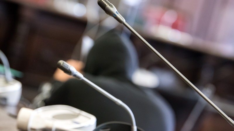 Ein Angeklagter sitzt im Oberlandesgericht im Saal.