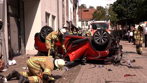 Ein völlig zerstörtes Fahrzeug liegt auf dem Dach.