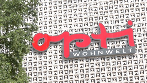 Zu sehen ist das Logo vom Opti WOHNWELT an der Gebäudefront.