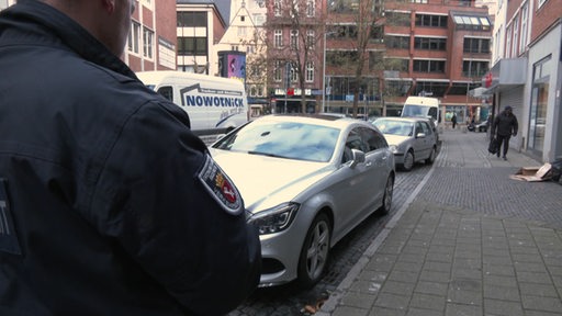 Zu sehen ist ein Mitarbeiter des Ordnungsamtes, welcher einen Falschparker aufschreibt.