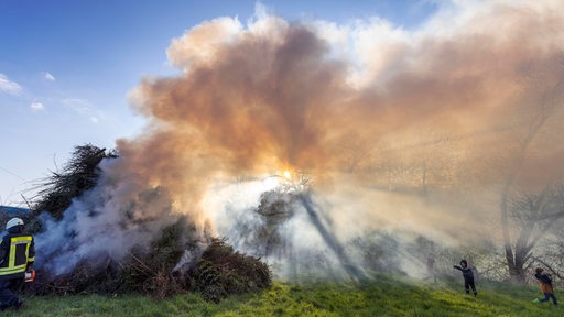 Ein Osterfeuer wird angezündet und qualmt sehr stark. 