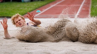 Para-Weitspringer Joel de Jong wirbelt bei seiner Landung jede Menge Sand auf.