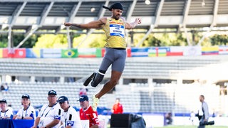 Para-Athlet Leon Schäfer bei seinem WM-Weitsprung hoch oben in der Luft.