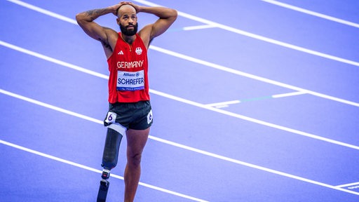 Para-Athlet Leon Schäfer steht gebannt mit verschränkten Händen auf dem Kopf nach dem 100-Meter-Sprint bei den Paralympiscs in Paris auf der Bahn und wartet auf das Ergebnis.