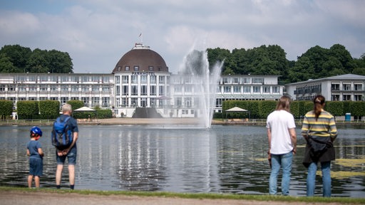 Spaziergänger laufen am Hollersee vor dem Parkhotel in Bremen vorbei.