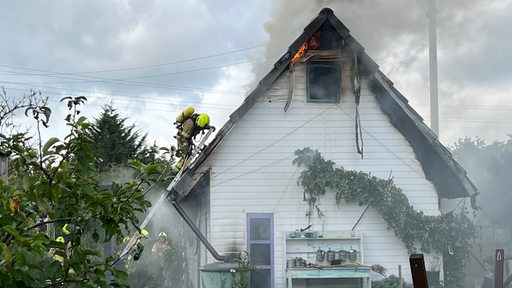 Feuerwehrleute löschen ein Feuer in einer Parzelle.