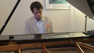 Pianist Hejazi sitzt an einem Flügel. 