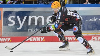 Ein Spieler der Pinguins leitet den Puck über das Eis.