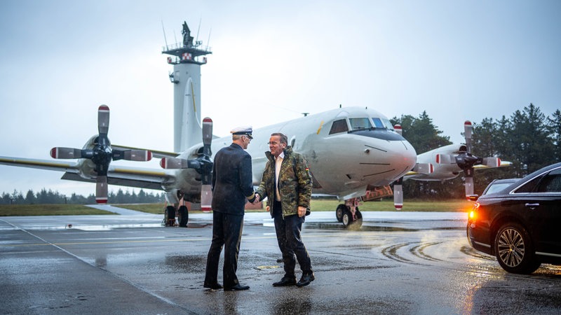 Zwei Männer stehen vor einem Flugzeug und schüttel sich die Hände.