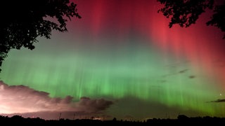 Am Nachthimmel ist ein großflächiges Polarlicht zu sehen.