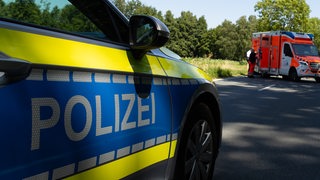 Ein Streifenwagen der Polizei steht mit Schriftzug an einem Unfallort