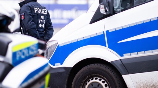 Ein Polizist steht zwischen Einsatzfahrzeugen