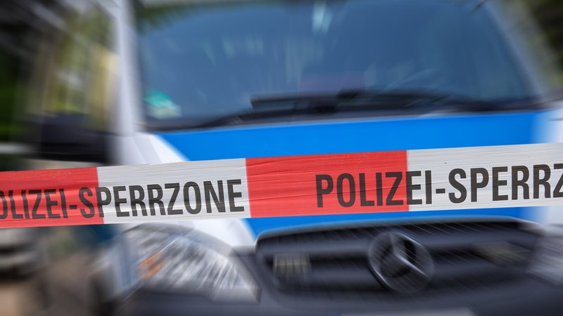 Polizeiabsperrung mit Polizeiauto im Hintergrund