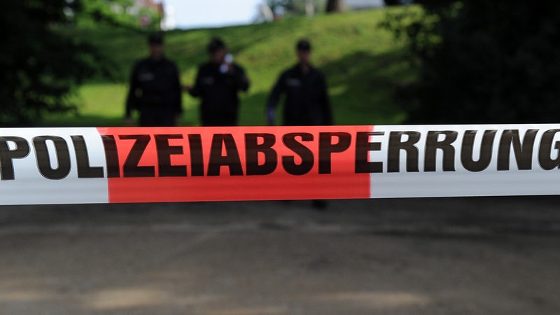 Ein rot-weißes Flatterband mit der Aufschrift "Polizeiabsperrung"