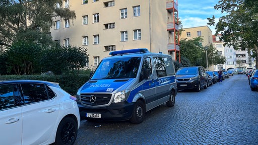 Ein Polizeiauto steht vor einem Wohnhaus.